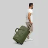 A man is walking and pulling a green duffle bag on wheels. Produktbild-Vorschau