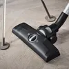 A close-up shot of a vacuum cleaner head on a wooden floor. Produktbild-Vorschau