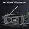 A black portable radio with an extended antenna is displayed against a dark, rocky background with some greenery on the right. Podgląd zdjęcia produktu