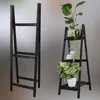Two black wooden ladder shelves, one empty and one with plants and decorative items. Produktbild-Vorschau
