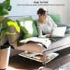 A woman is using a laptop on a bed with a portable laptop table. Produktbild-Vorschau
