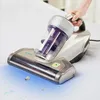 A hand is holding a handheld vacuum cleaner over a white surface, possibly a mattress, with blue light emanating from the vacuum head and small illustrations of dust mites. Náhled obrázku produktu