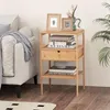 A bedside table with books and picture frames next to a sofa. Podgląd zdjęcia produktu