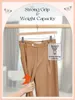 A pair of brown pants hanging on a hanger, being tested for its weight capacity. Overlay text and graphics highlight the product's features. Produktbild-Vorschau