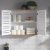 A bathroom wall cabinet is open, displaying its contents on two shelves. The top shelf holds a lotion bottle, a jar, and two small decorative items. The bottom shelf contains several rolls of toilet paper and neatly folded towels. The cabinet has white sla Náhled obrázku produktu