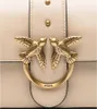 A close-up shot of a beige handbag's clasp, featuring two golden birds and the brand name 'PINKO'. Podgląd zdjęcia produktu