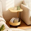 A yellow side table with a cloud-shaped top is placed next to a sofa and a bed. The table has a lower shelf containing books and a box. A mug and a calendar are on the top surface. Produktbild-Vorschau