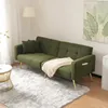 A green sofa with gold legs is placed on a fluffy gray rug in a well-lit room. A blanket is draped over the sofa, and a small side table with a marble top and gold base is next to it. Anteprima dell’immagine prodotto