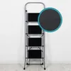 A gray metal step ladder with four black steps is shown against a white wall and light wood floor. A circular inset highlights the textured surface of one of the steps. Náhled obrázku produktu