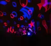 A projector casts colorful ocean-themed shapes onto a dark background, with the projector itself visible in the foreground. Voir les images du produit