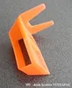 An orange plastic holder for a Tetra Pak box is shown on a gray textured surface. Produktbild-Vorschau
