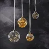 Four clear glass ornaments filled with warm white LED lights hang from white ribbons against a dark, textured background. Produktbild-Vorschau