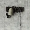 A wall-mounted coat rack with a hat, camera, and a strap hanging from it. Náhľad obrázku produktu