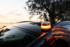 A hand is reaching towards a warning light on top of a car during sunset. Produktbild-Vorschau