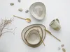 A flat lay of a stoneware dinnerware set with gold cutlery and decorative stones. Produktbild-Vorschau