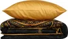 A stack of bedding, including a gold pillow and a black and gold patterned duvet or comforter. Produktbild-Vorschau