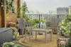 A balcony setting with outdoor furniture and plants, overlooking a city skyline. Náhled obrázku produktu