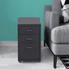 A gray metal filing cabinet with three drawers is placed next to a gray sofa. Podgląd zdjęcia produktu