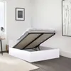 A white bed frame with the mattress lifted, revealing storage space underneath. The bed is in a minimalist bedroom setting with artwork on the wall. Produktbild-Vorschau