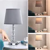 A collage of images showing a table lamp with a grey shade and crystal accents, with USB charging ports on the base. The lamp is shown in different lighting conditions. Produktbild-Vorschau