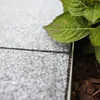 A close-up view of paving stones next to a plant and mulch. Produktbild-Vorschau