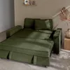 A green sofa bed is shown in a room with a textured wall and a wooden side table with a dried plant. Anteprima dell’immagine prodotto