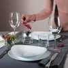 A person is setting a table with glassware and plates. Produktbild-Vorschau