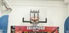 A basketball hoop mounted on a wall above a banner celebrating champions. Produktbild-Vorschau
