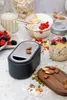 A breakfast scene with a grater, berries, nuts, and oatmeal in a jar and bowl. Produktbild-Vorschau