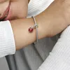 A close-up shot of a person's arm wearing a Pandora bracelet with a ladybug charm. Podgląd zdjęcia produktu