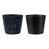 Two black planters are shown side-by-side against a white background. The planter on the left has a decorative, textured outer shell, while the planter on the right is a simple, solid cylinder. Podgląd zdjęcia produktu