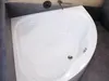 A white corner bathtub with dark gray tiled walls and floor. Produktbild-Vorschau