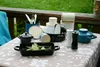 A collection of kitchenware and cookware arranged on a table outdoors. Produktbild-Vorschau