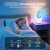 A woman sleeping peacefully in bed next to a bedside table with a white fan-like device emitting colorful lights. Náhled obrázku produktu