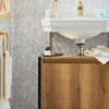 A bathroom vanity with a sink and cabinet, featuring a herringbone tile backsplash. Náhľad obrázku produktu