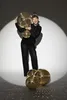 A woman in a sparkly black outfit holds up several disco balls, with more disco balls on the floor. Anteprima dell’immagine prodotto