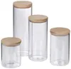 Four clear glass jars with wooden lids are arranged on a white background. Produktbild-Vorschau