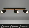 A three-light ceiling spotlight fixture with adjustable heads mounted on a wooden and black base, shown against a neutral gray background. Produktbild-Vorschau