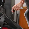 A person's hand is adjusting a knob on an indoor cycling bike. Produktbild-Vorschau