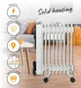 A white oil-filled radiator is shown in a living room setting, with marketing text and icons highlighting its features. Náhled obrázku produktu