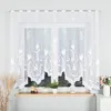 A white lace curtain with a floral pattern hanging on a window. Produktbild-Vorschau