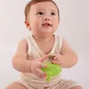 A baby is holding a green teether. Podgląd zdjęcia produktu