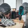 A person wearing work gloves is using a cordless drill to screw into a piece of wood. Produktbild-Vorschau