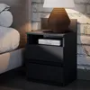 A bedside table with a lamp and books next to a bed. Náhled obrázku produktu