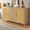 A modern wooden sideboard with rattan doors and gold handles, displayed in a well-lit room with a rug and wall decor. Voir les images du produit