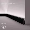 A black skirting board is installed in the corner of a room, with subtle lighting highlighting the wall. Podgląd zdjęcia produktu