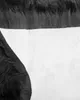 A close-up view of a black sheepskin rug with a white backing. The image focuses on the texture and material of the rug. Produktbild-Vorschau