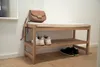 A wooden shoe bench with a padded seat, placed against a white wall in a hallway. A brown handbag is on top of the bench, and shoes are on the shelves. Náhled obrázku produktu