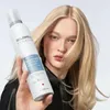 A woman holds a bottle of Goldwell StyleSign Volume Bodifying Control Mousse in front of her blonde hair. Podgląd zdjęcia produktu