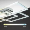A modern, geometric ceiling light fixture with interconnected rectangular frames, shown against a contrasting background. Produktbild-Vorschau